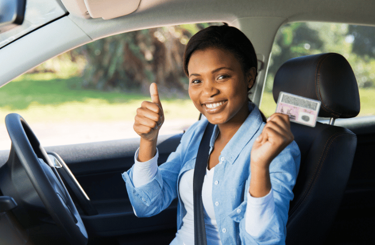 Happy young learner's license recipient proudly holding her driver's license.